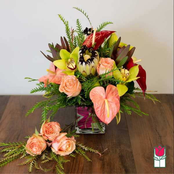 Tropical bouquet in a square glass vase with peach roses and pink anthuriums