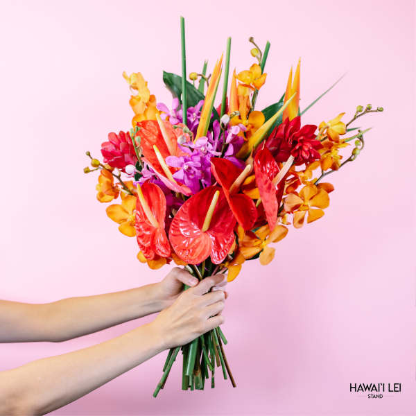 Tropical bouquet with red anthuriums and orange orchids against a pink background