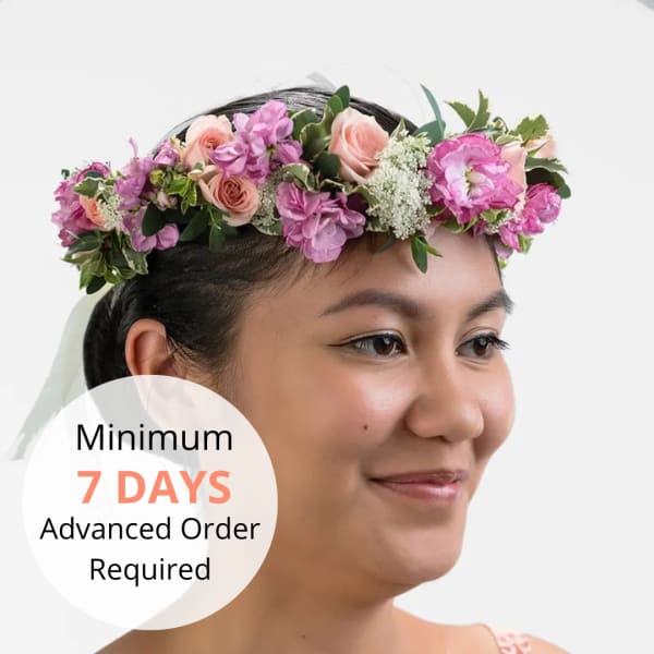 Woman wearing a pink and peach rose flower crown with white filler blooms.