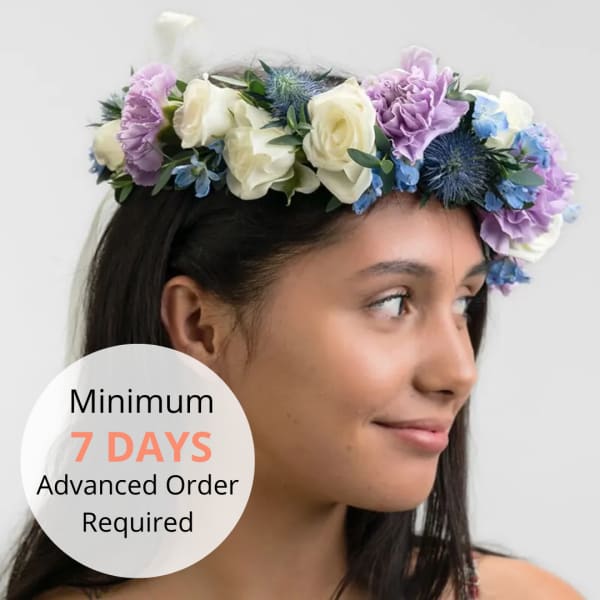 Floral crown of white roses, lavender blooms, and blue accent flowers worn on a woman's head