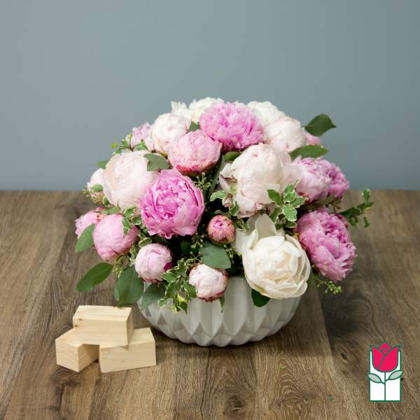Pink and white peony arrangement in a white bowl vase