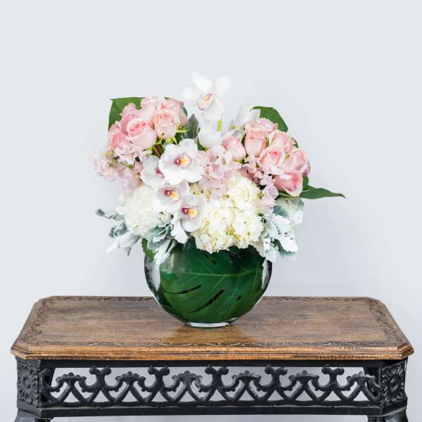 Pink and white flower arrangement in a round glass vase