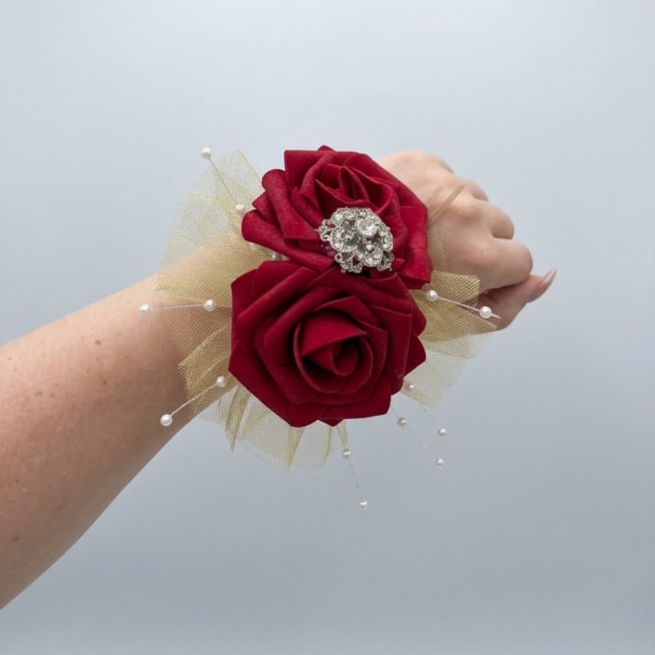 Red rose wrist corsage with tulle and pearl accents on a wrist