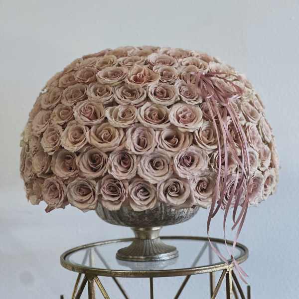 Round bouquet of pale pink roses in a pedestal vase with ribbon