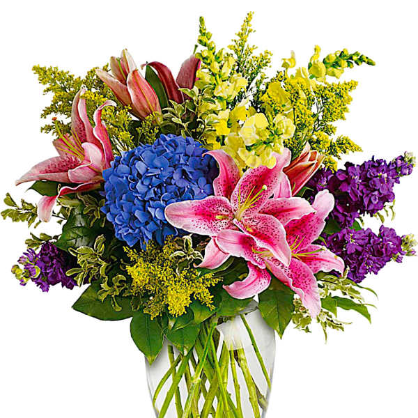 Bouquet of pink lilies, blue hydrangea, and purple flowers in a glass vase