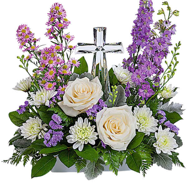 White roses and purple flowers arranged around a clear cross