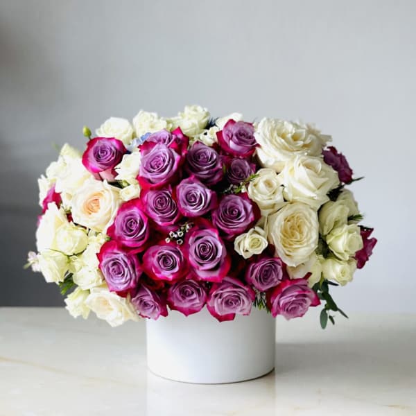 Bouquet of pink, purple, and white roses in a white box