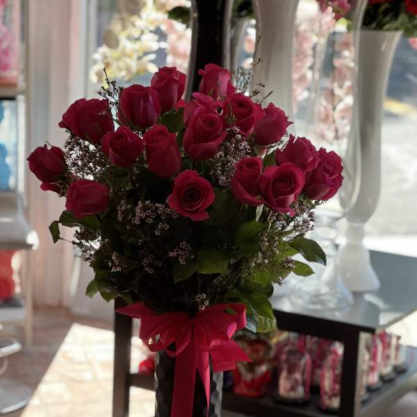 Bouquet of hot pink roses in a black vase with a pink ribbon