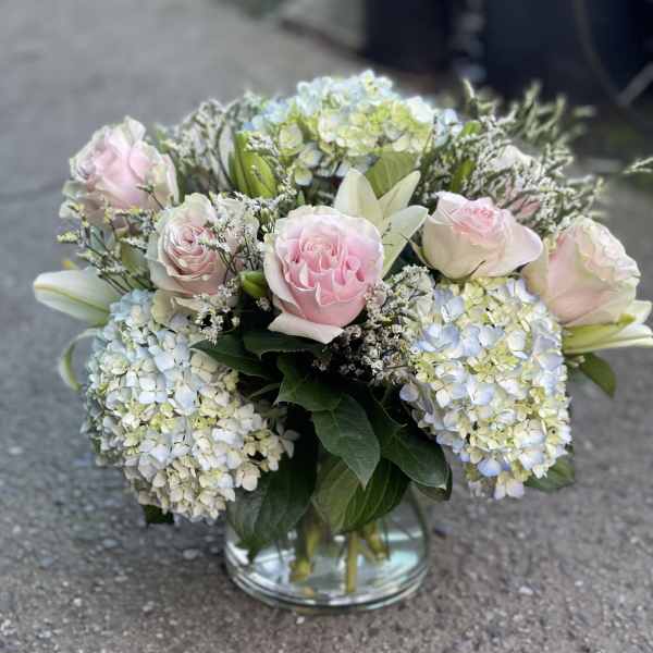 Pink roses and blue hydrangeas arranged in a glass vase