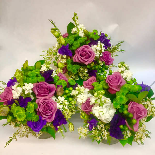 Purple roses and white flowers arranged in a low cluster