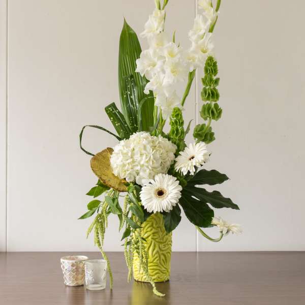 White floral arrangement in a lime green vase with gerbera daisies and tall blooms