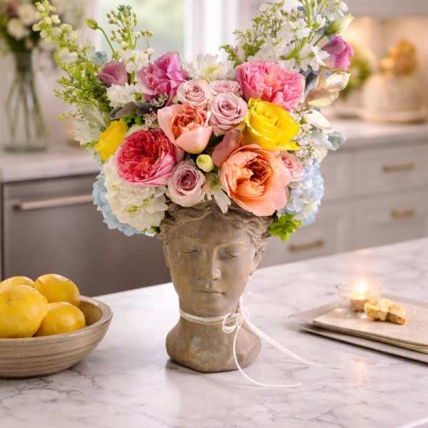 Colorful flower arrangement in a sculpted bust vase on a kitchen counter