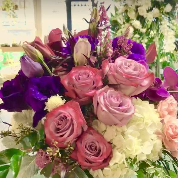 Bouquet of pink and purple roses with white hydrangea in a glass vase