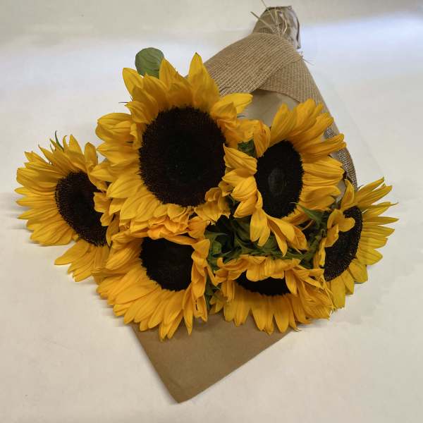 Bouquet of yellow sunflowers wrapped in burlap and kraft paper
