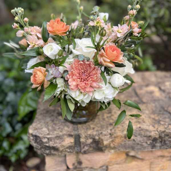 Mixed bouquet of peach, white, and pink flowers in a glass vase