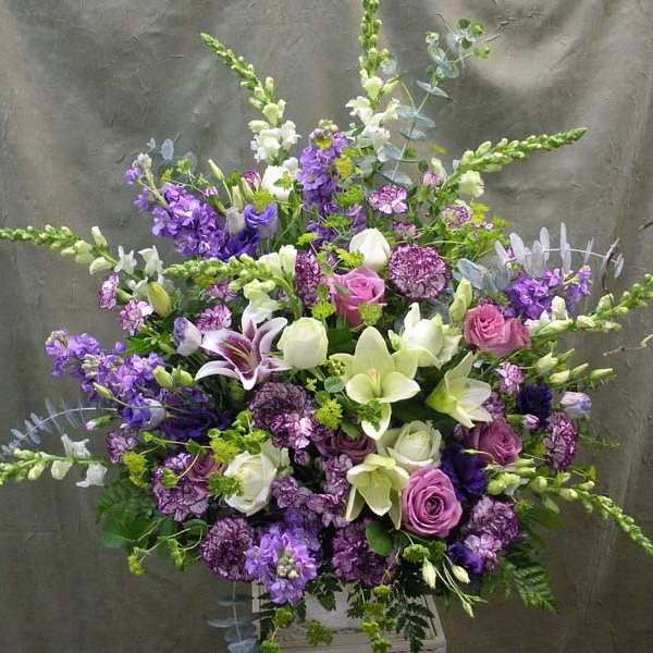 Large purple and white floral arrangement with lilies and roses