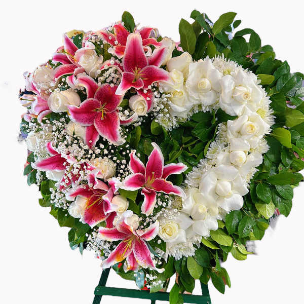 Heart-shaped floral wreath with pink lilies and white roses on an easel