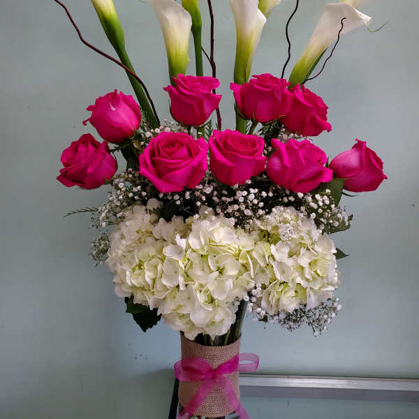 Pink roses and white calla lilies arranged in a glass vase