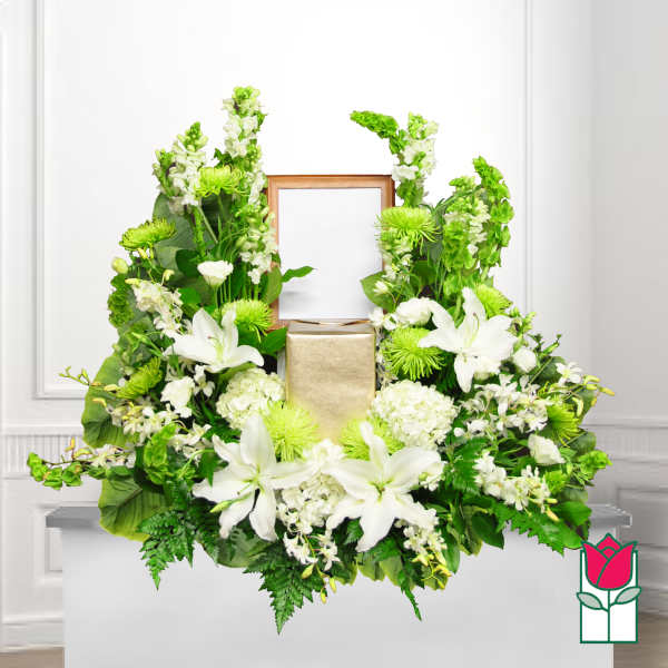 White lilies and green flowers arranged around a framed center and gold box