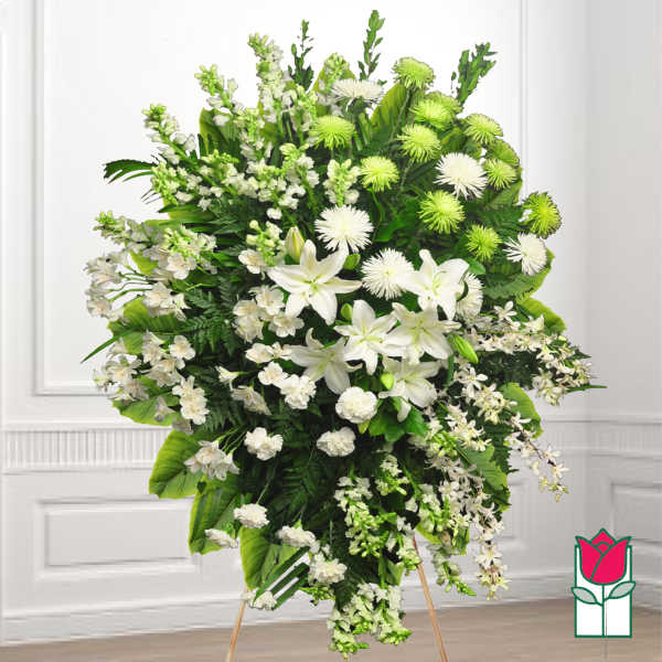Large white and green funeral spray with lilies and orchids on a stand