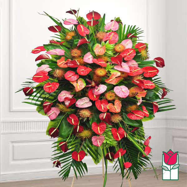 Large standing arrangement of red and pink anthuriums with tropical foliage