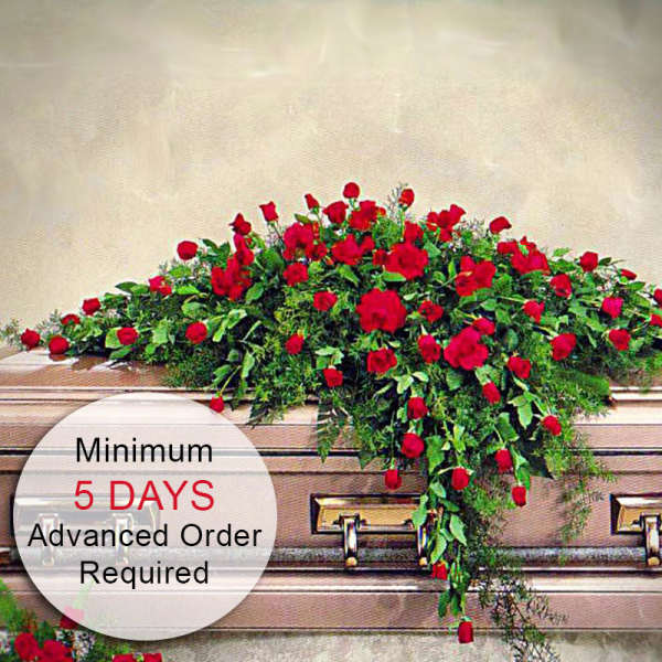 Red rose casket spray draping over a closed bronze casket