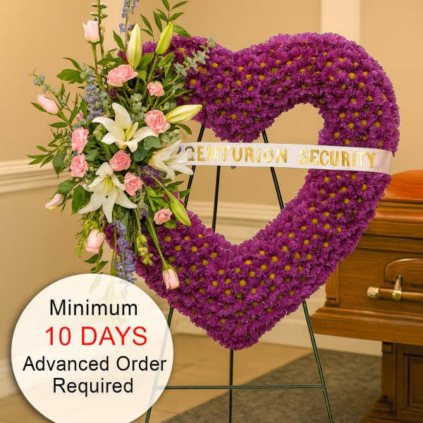 Tall purple heart-shaped funeral wreath with pink and white flowers on a stand