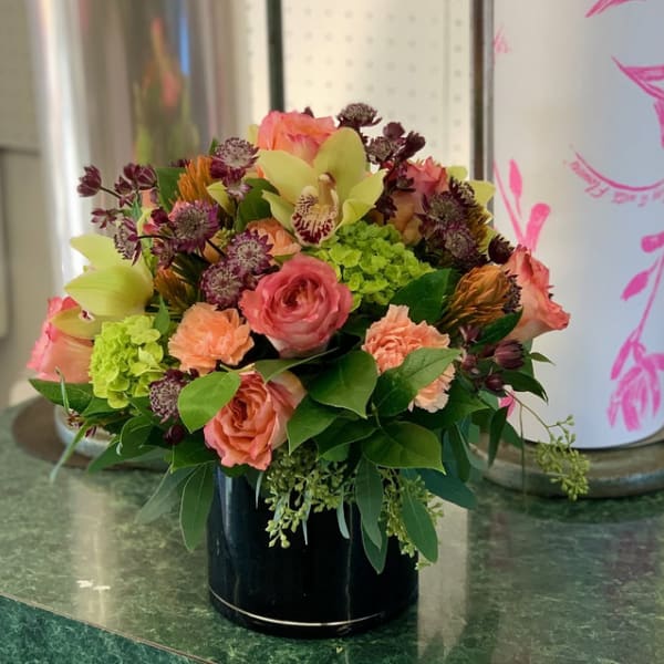 Pink and peach mixed bouquet in a black vase