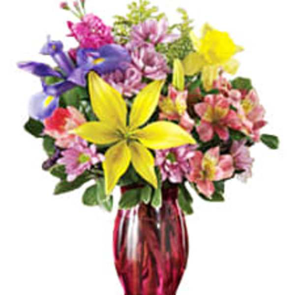 Colorful bouquet of mixed flowers in a red glass vase