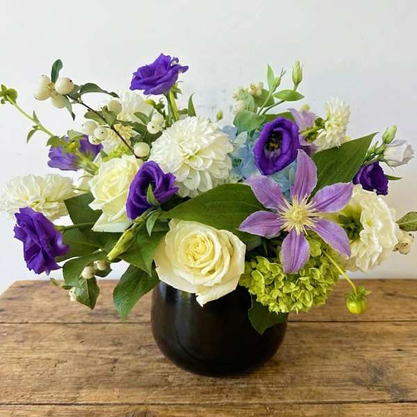 Purple and white mixed bouquet in a dark vase