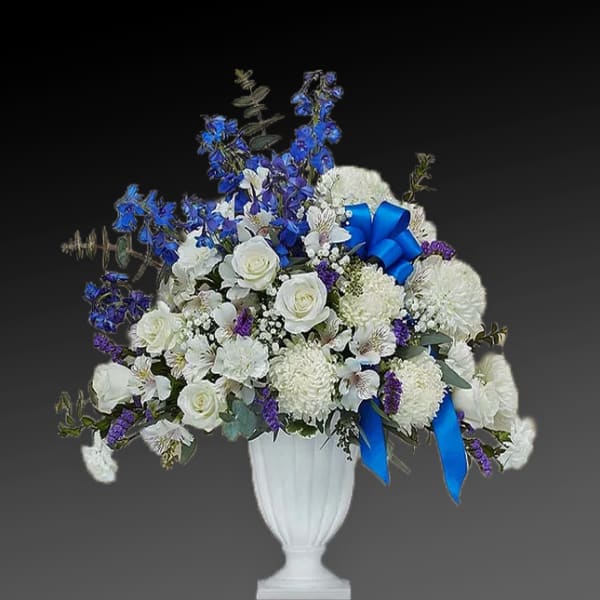 White and blue floral arrangement in a white urn vase