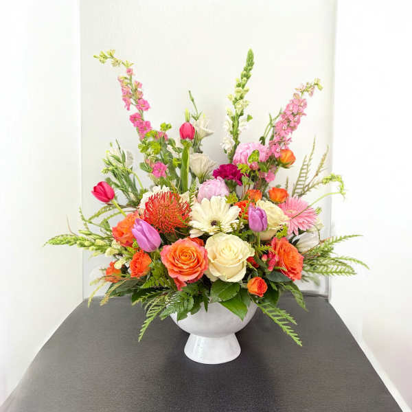 Colorful mixed flower arrangement in a white pedestal vase