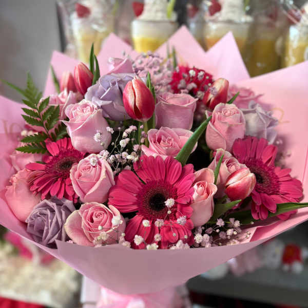 Pink bouquet with roses, gerbera daisies, and tulips wrapped in pastel paper