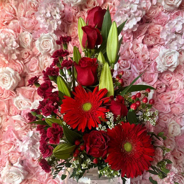 Red roses and gerbera daisies arranged in a clear glass vase