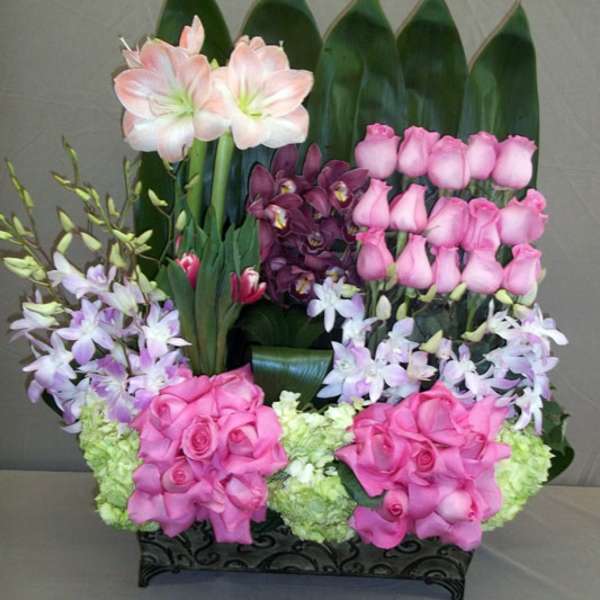 Pink roses and orchids arranged in a black rectangular container