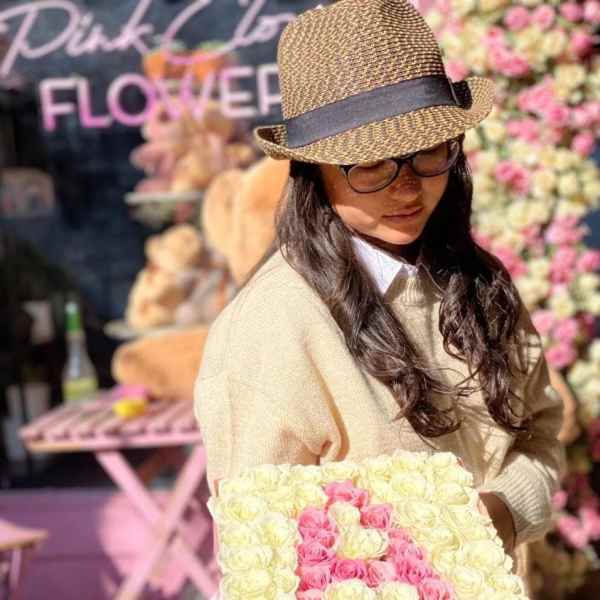 Woman holding a pink box filled with cream and pink roses