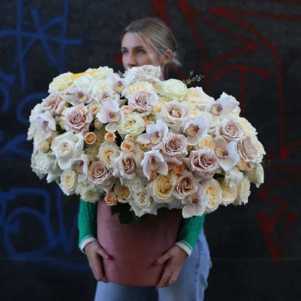 Large bouquet of pale roses and white orchids in a pink container