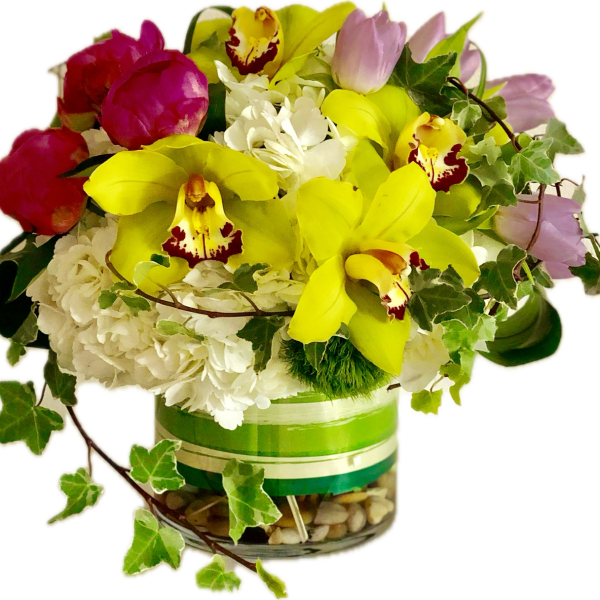 Bouquet of yellow orchids, pink tulips, and white flowers in a glass vase