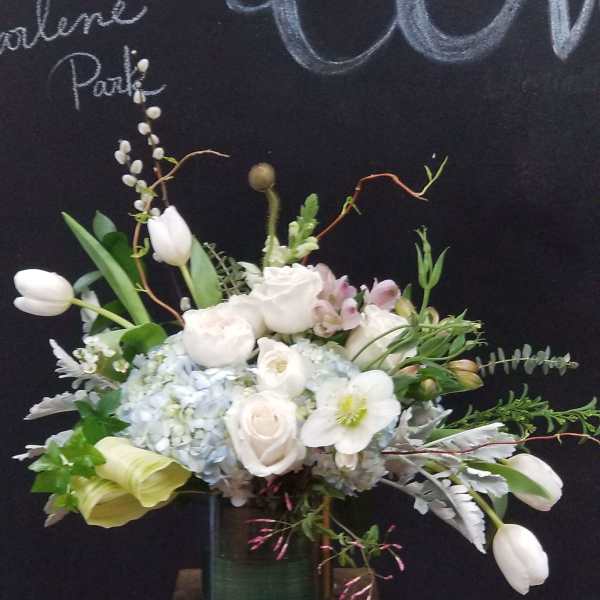 White tulips, roses, and hydrangeas arranged in a green vase