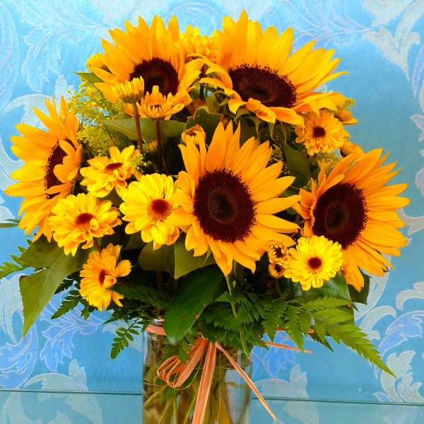 Sunflower and yellow daisy bouquet in a clear glass vase