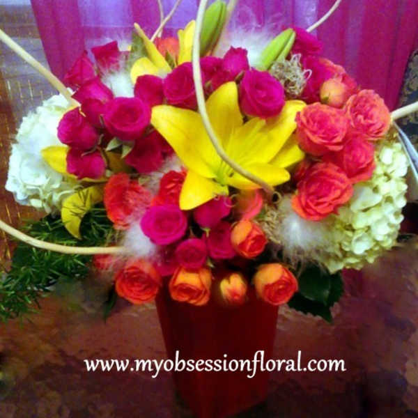 Bright mixed bouquet with yellow lilies and pink roses in a red vase