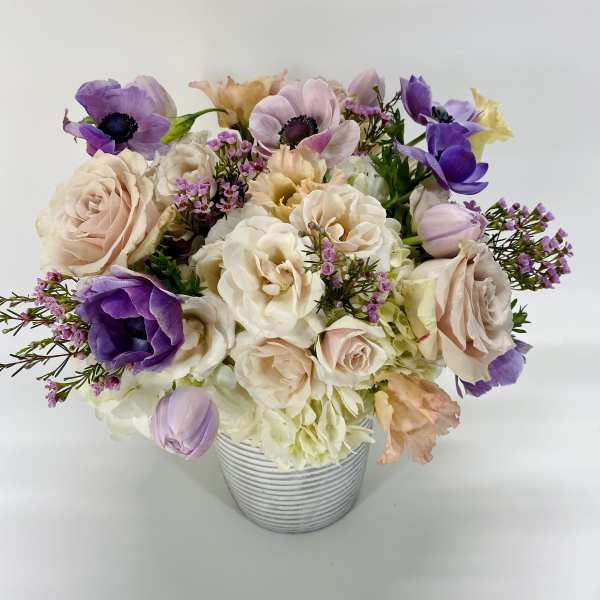 Pastel bouquet of roses and purple anemones in a striped vase