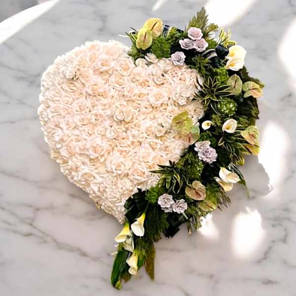 Heart-shaped floral arrangement with pale roses and mixed white flowers
