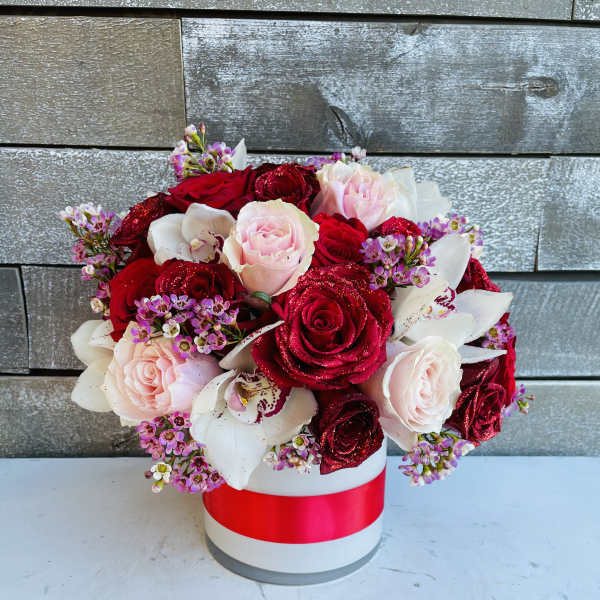 Bouquet of red and blush roses with white orchids in a round box