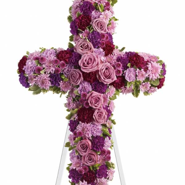 Cross-shaped floral tribute with pink and purple roses and mums on an easel