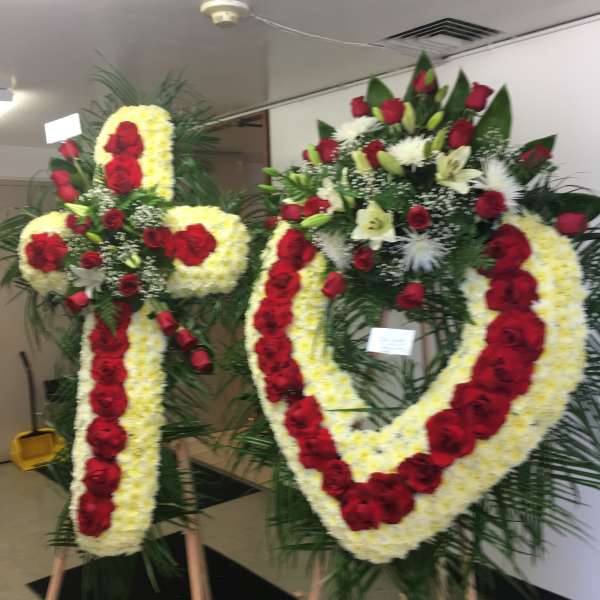 Two large floral funeral wreaths on easels with red and white flowers