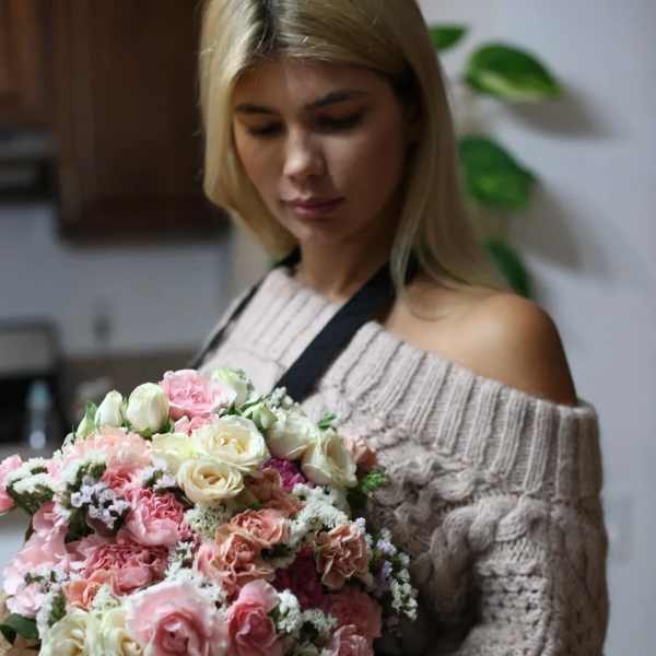 Woman holding a large bouquet of pink and cream roses