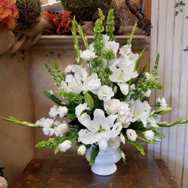 White lilies and roses arranged in a white vase