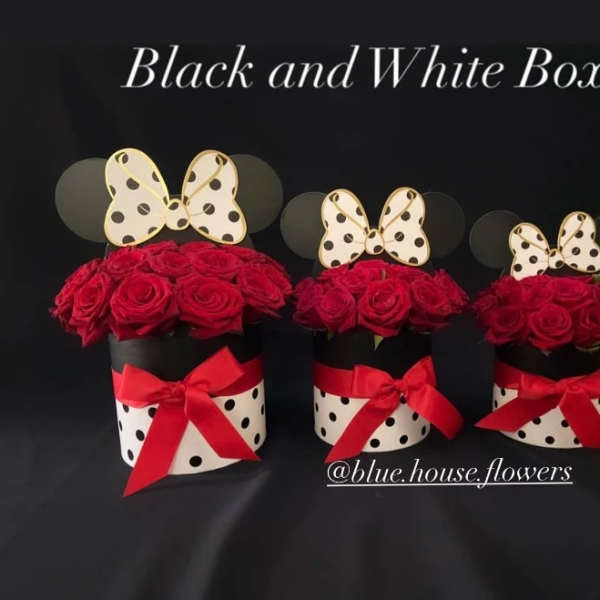 Three red rose arrangements in black-and-white polka dot boxes with red bows