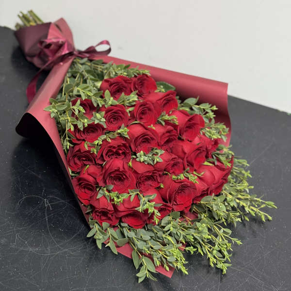 Bouquet of red roses wrapped in burgundy paper with a ribbon